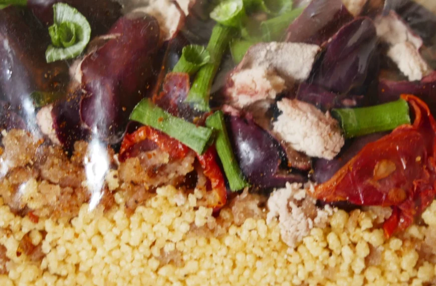 Dehydrated couscous, tomato, chives, kidney beans, and chicken mixed together colourfully.
