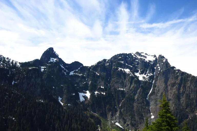 The craggy Blanshard and Edge Peaks thrust into a blue sky dotted with clouds.