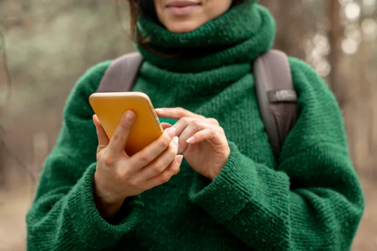 A hiker looks at her phone in the forest.