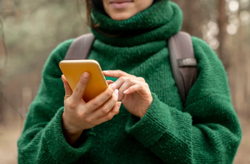A hiker looks at her phone in the forest.