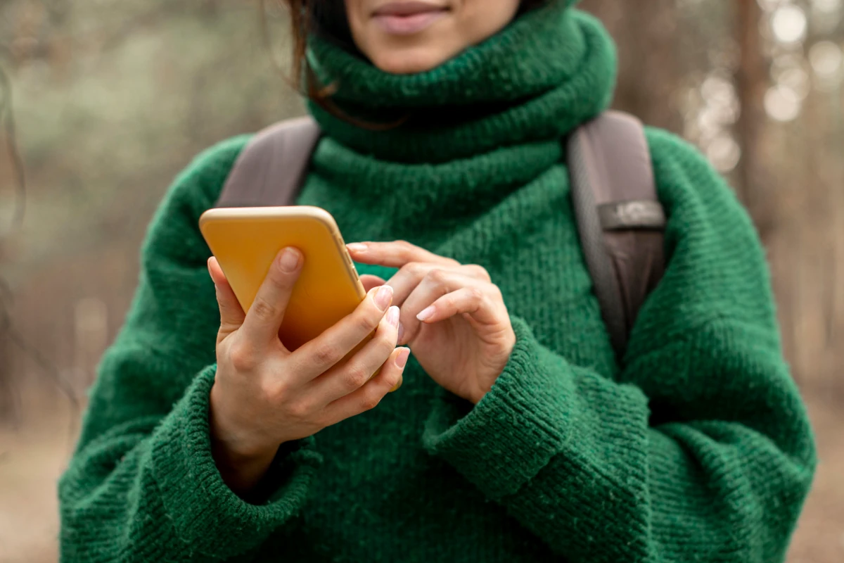 A hiker looks at her phone in the forest.