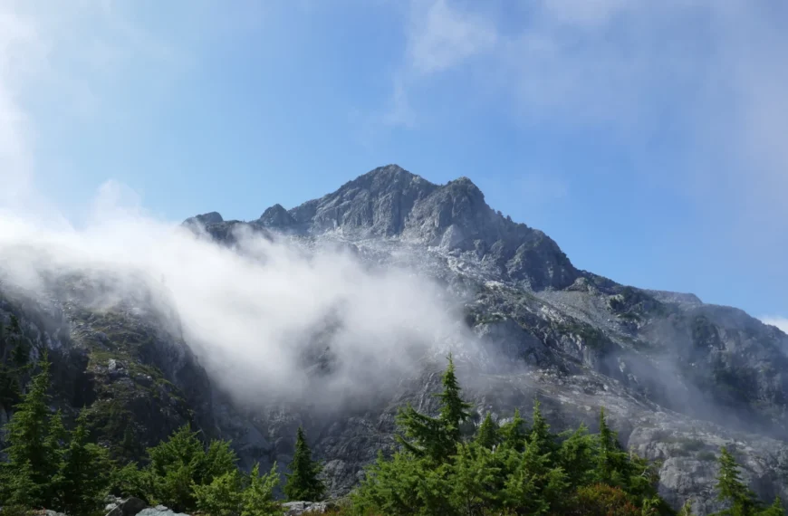Mist pulls back to reveal a mountain summit.