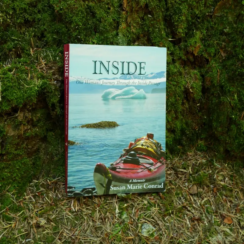 The book "Inside" by Susan Marie Conrad sits against a tree.