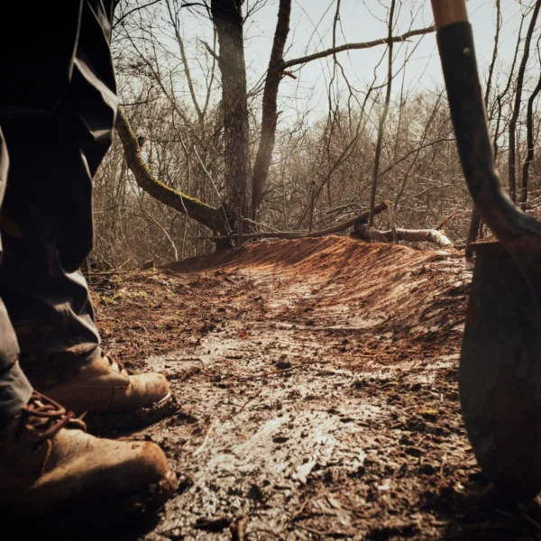 Boots and a shovel are visible in front of a freshly maintained trail.