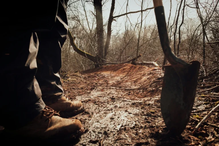 Boots and a shovel are visible in front of a freshly maintained trail.