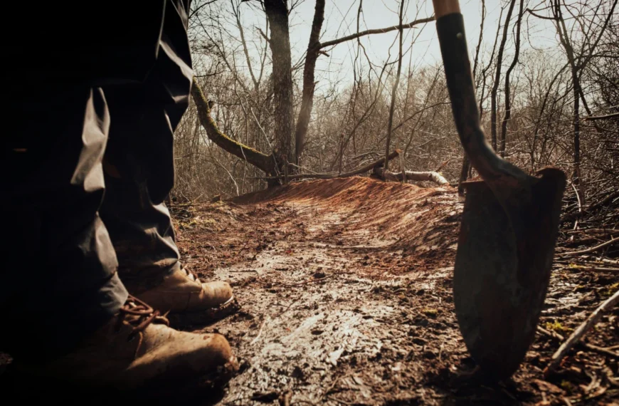 Boots and a shovel are visible in front of a freshly maintained trail.