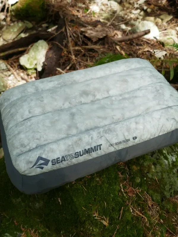 An Aeros Down pillow sits on a rock.