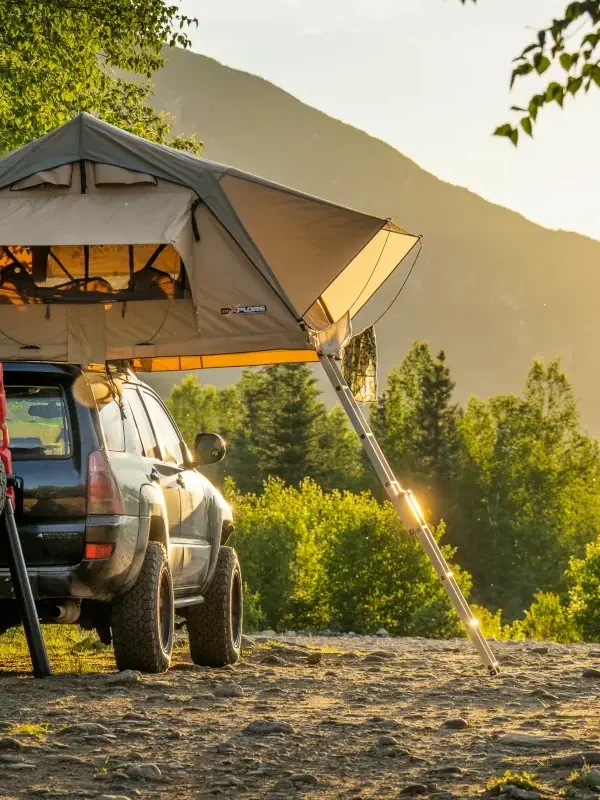A vehicle with a rooftop tent camps on a industry road.