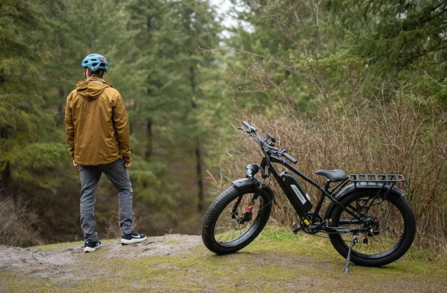 A man stands next to an e-bike in the forest.