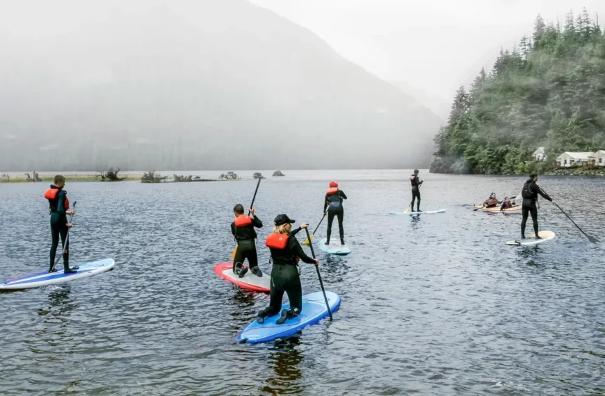 Paddleboarders wearing PFDs paddle on a cloudy lake.